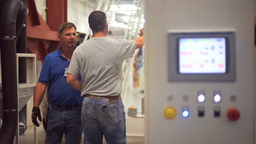 Image of two men talking in a workplace