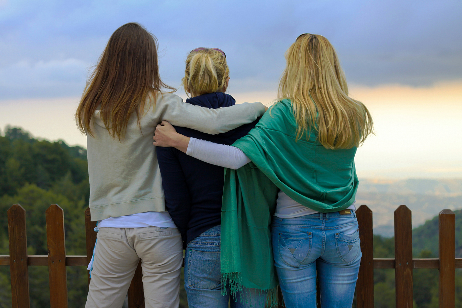 Photo of mom and two teenage daughters looking at the sunrise