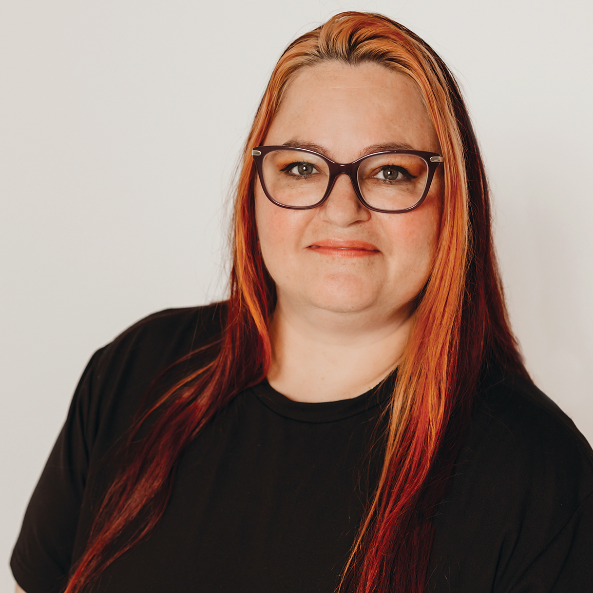 Photo of woman with glasses and long hair in front of blank background