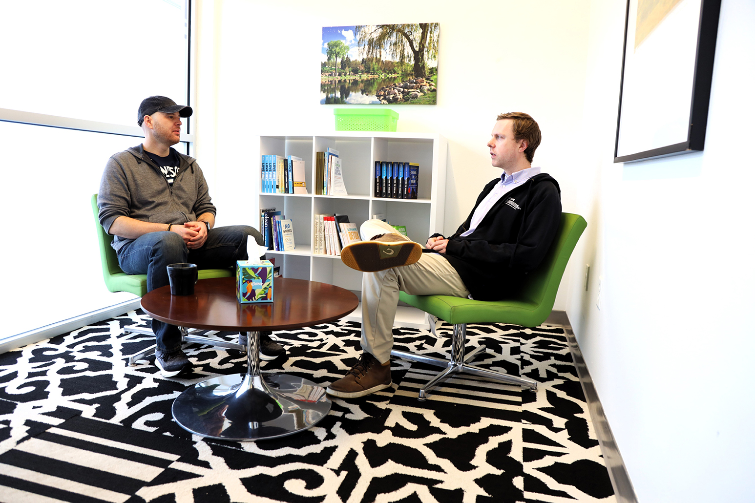 Photo of two men sitting and talking in light-filled room