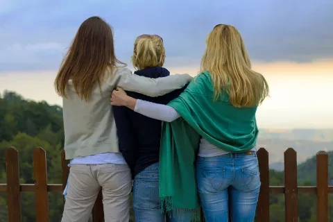 Photo of mom and two teenage daughters looking at the sunrise