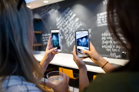 Photo of two women taking pictures of chalkboard