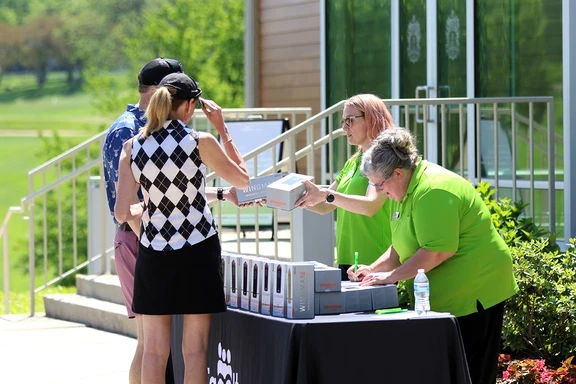 Photo of volunteers giving player gifts at annual golf tournament