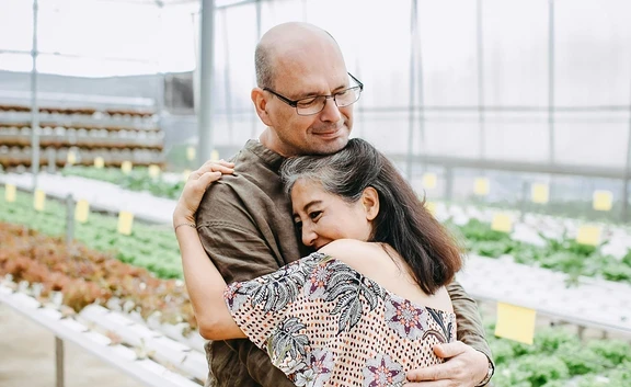 Fotografía de una pareja mayor abrazándose en un invernadero