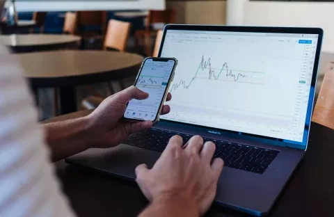 Photo of phone and computer screens displaying stocks