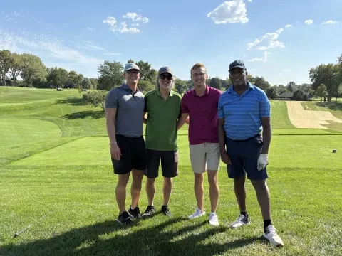 Fotografía de cuatro hombres en un campo de golf
