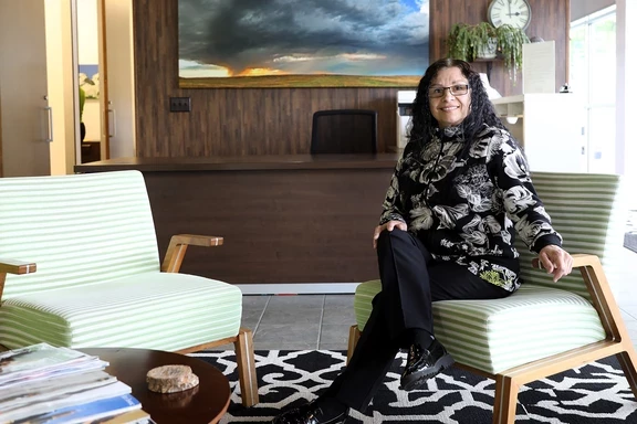 Photo of woman sitting and smiling at the camera in light-filled office