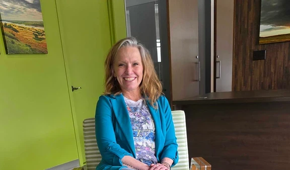 Foto de una mujer sentada y sonriendo en una habitación luminosa